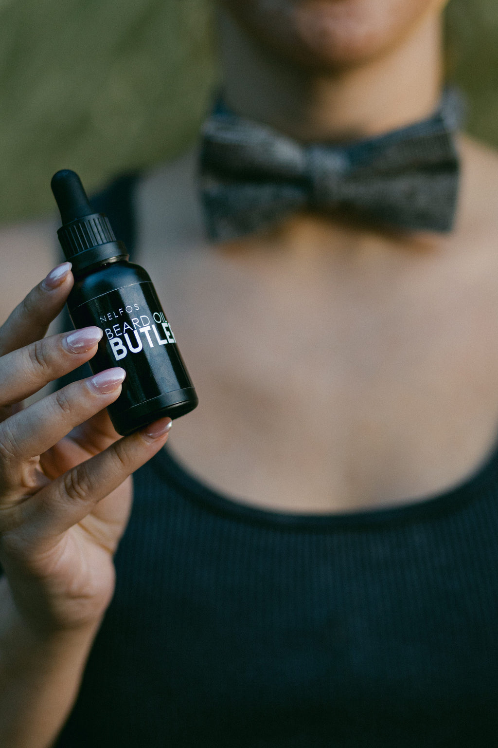 Person holding a black bottle labeled 'Beard Oil Build' with a blurred background