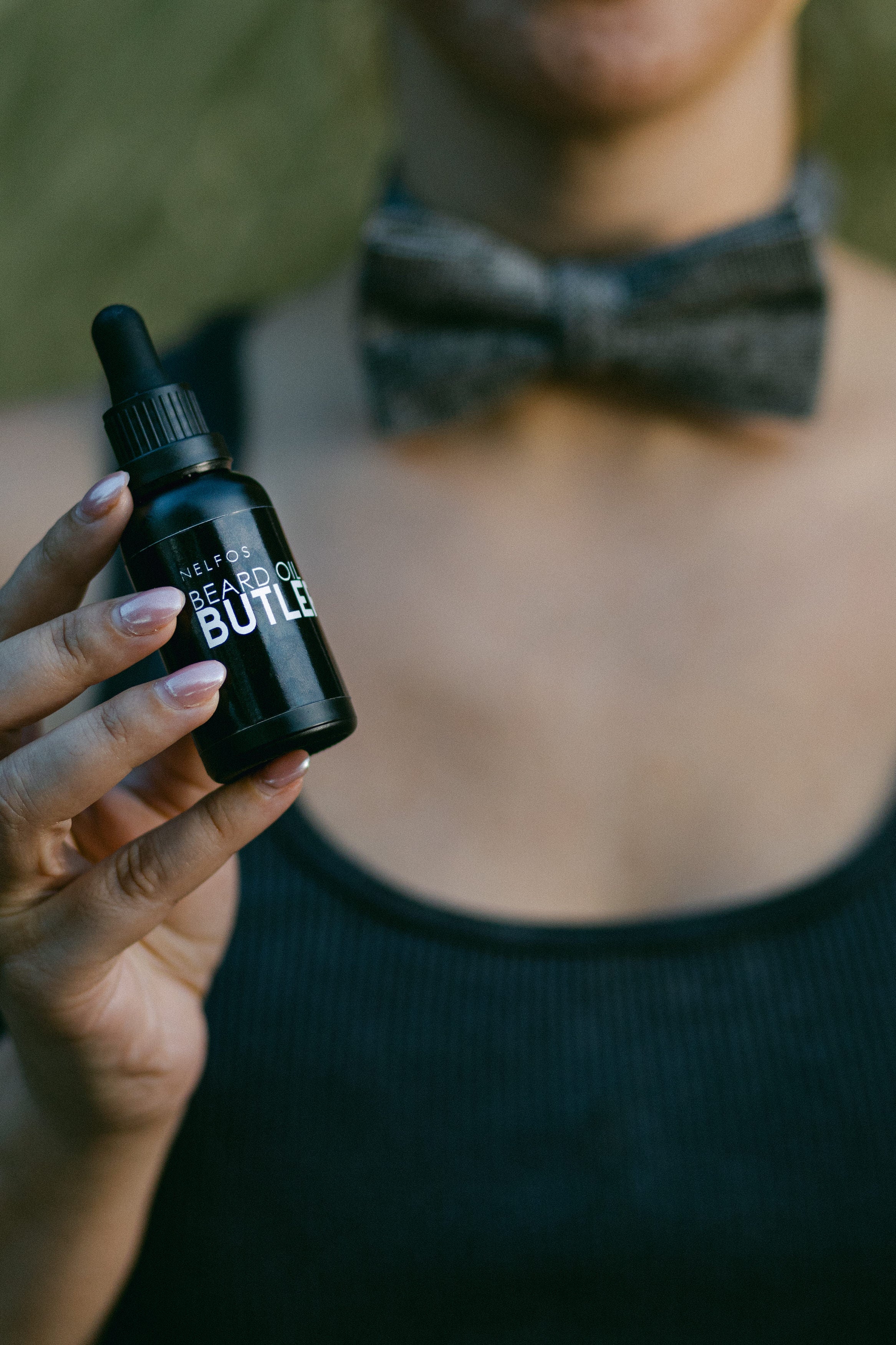 Person holding a black bottle labeled 'Beard Oil Build' with a blurred background